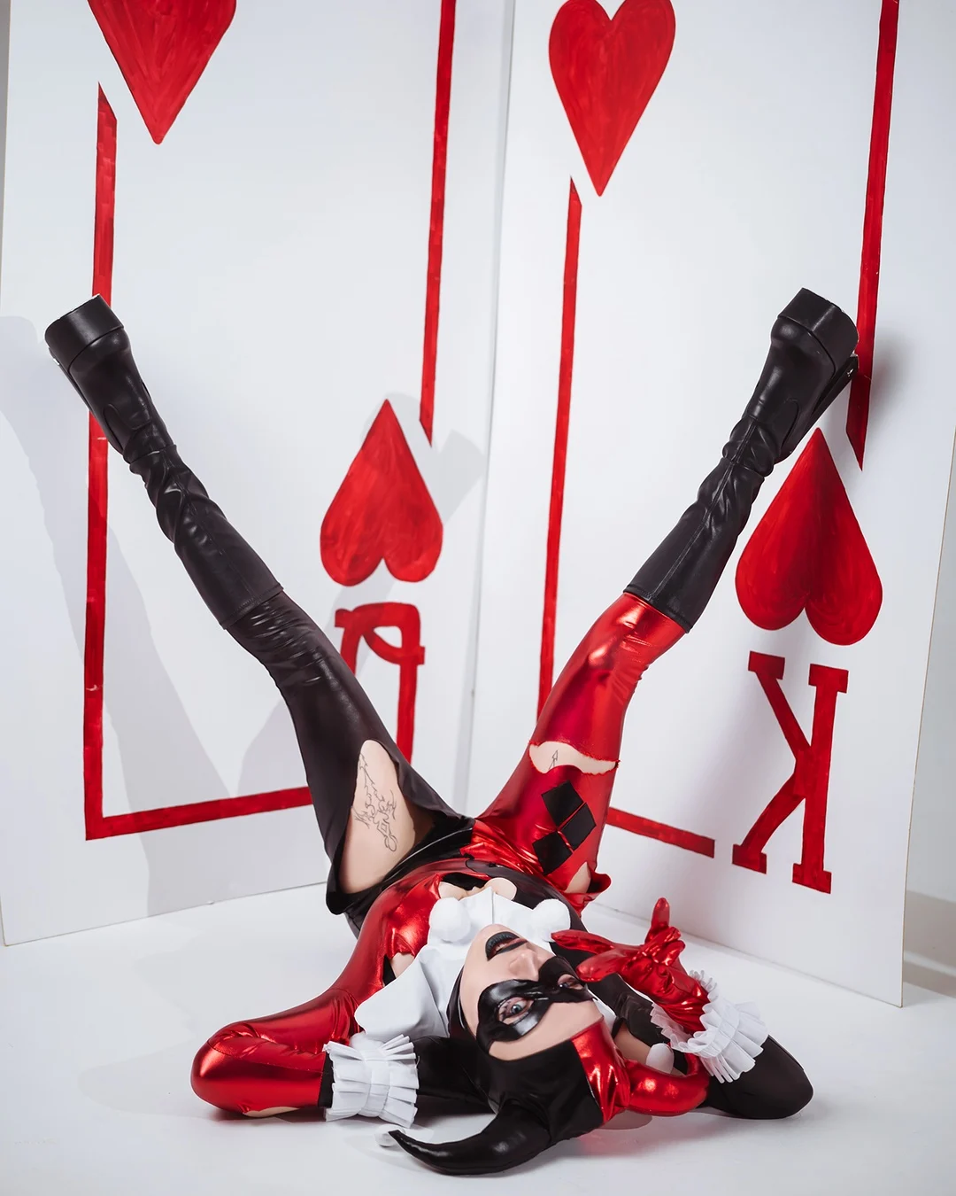 Ira in a red and black harlequin costume against oversized playing cards