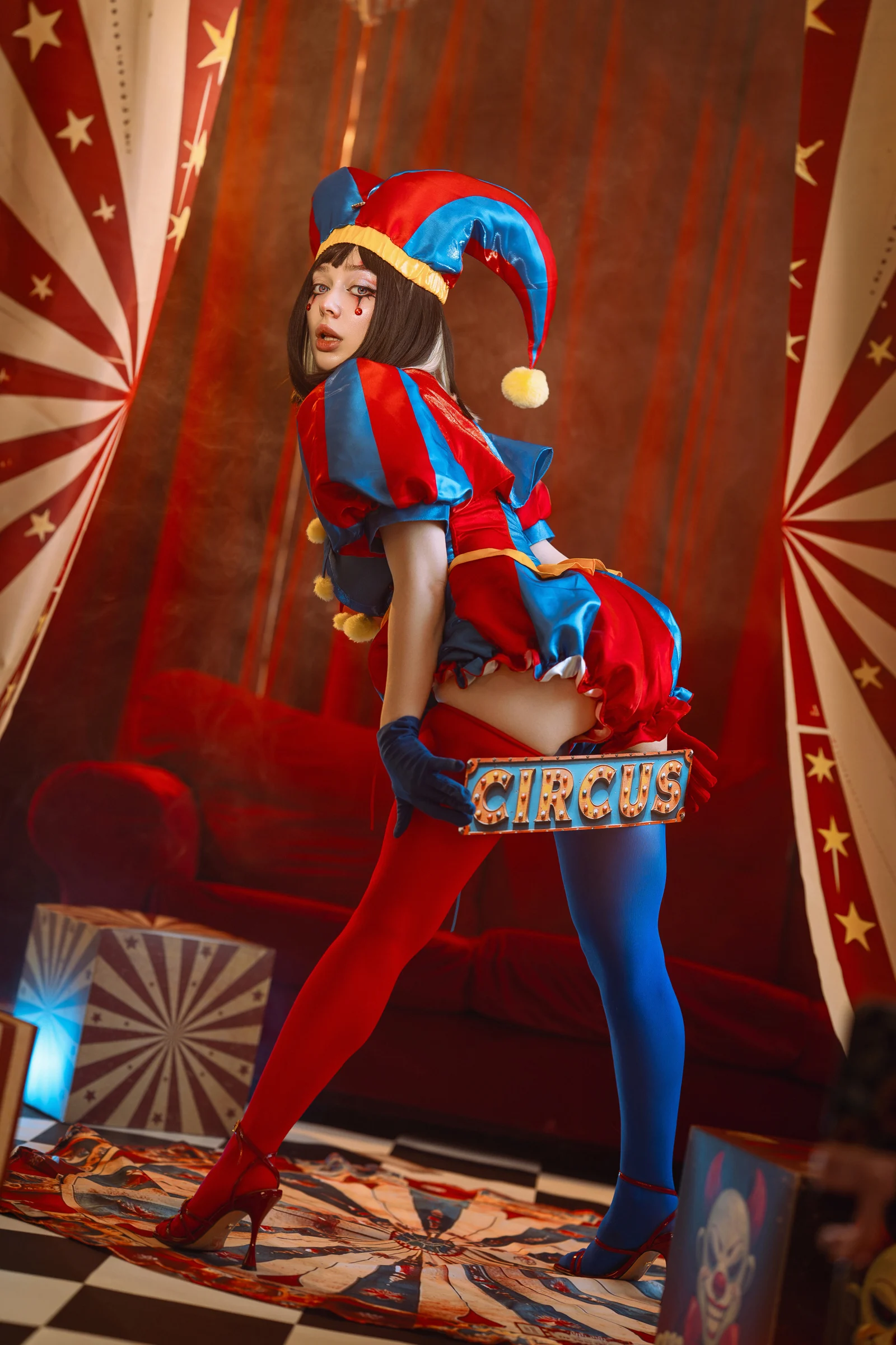Ira in a red and blue jester costume in a circus set